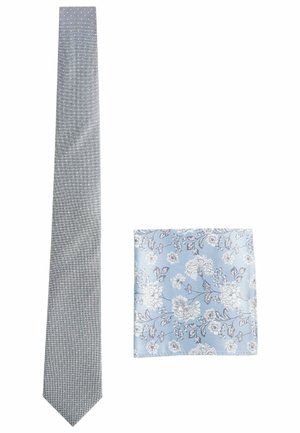 Grå slips med hvide polka-prikker og en matchende lommefyr med en blå baggrund og blomster mønstre i hvidt og gråt.