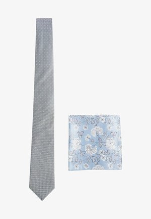 Szary krawat w białe kropki oraz pasująca poszetka z niebieskim tłem i wzorami kwiatowymi w białym i szarym kolorze.