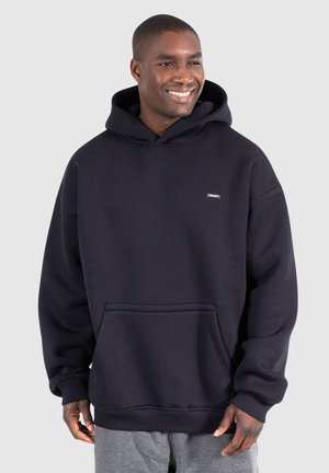 Marineblauwe hoodie gemaakt van zachte stof, met een kangoeroezak en geribbelde manchetten. Klein logo op de borst.