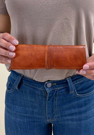 Pruun nahast rahakott, piklik ristkülikukujuline kuju, sile tekstuur, kinnitatud nahkrihmaga, millel on kontrastsete õmbluste detailid.