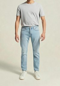 Jeans de denim azul claro con corte recto, combinados con una camiseta gris clara y zapatillas blancas. Textura suave, diseño casual.