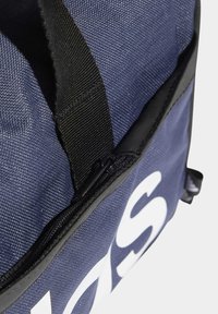 Borsa a viaggio blu navy in tessuto testurizzato, con manico nero a contrasto e zip. Grande testo bianco accentuato sul lato.