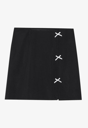 Black mini skirt with a smooth texture, featuring white crossed ribbons on the left side. Simple design with a straight cut.