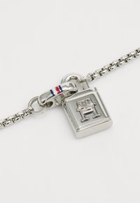 Bracciale in argento con un charm a forma di lucchetto rettangolare con una lettera "H" in rilievo e un accento tricromatico sulla chiusura.