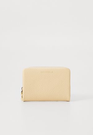 Cream leather wallet with textured surface, zip closure, and logo embossing on the front. Compact rectangular shape. Gold hardware accents.