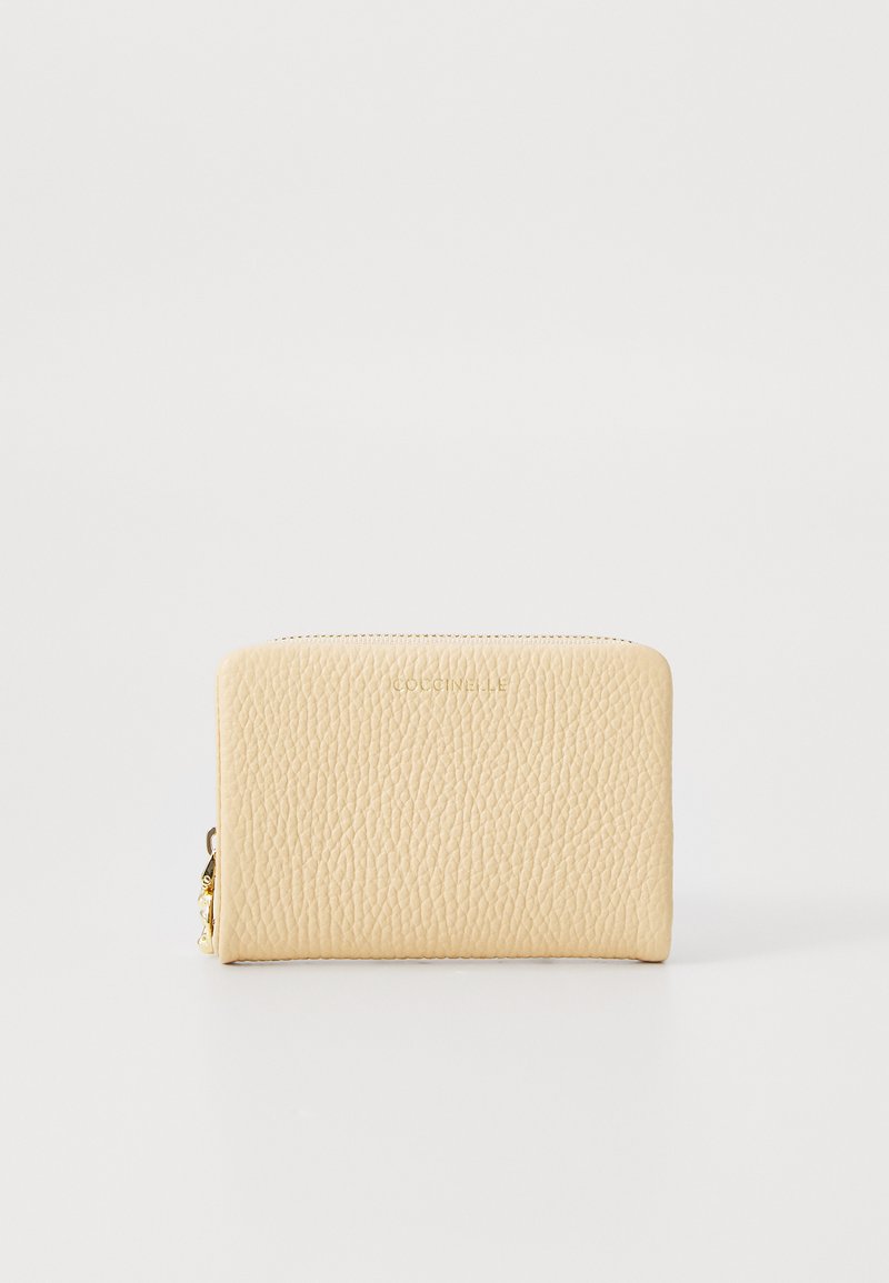 Carteira de couro creme com superfície texturizada, fecho em zip e logótipo em relevo na frente. Forma retangular compacta. Acessórios em dourado.