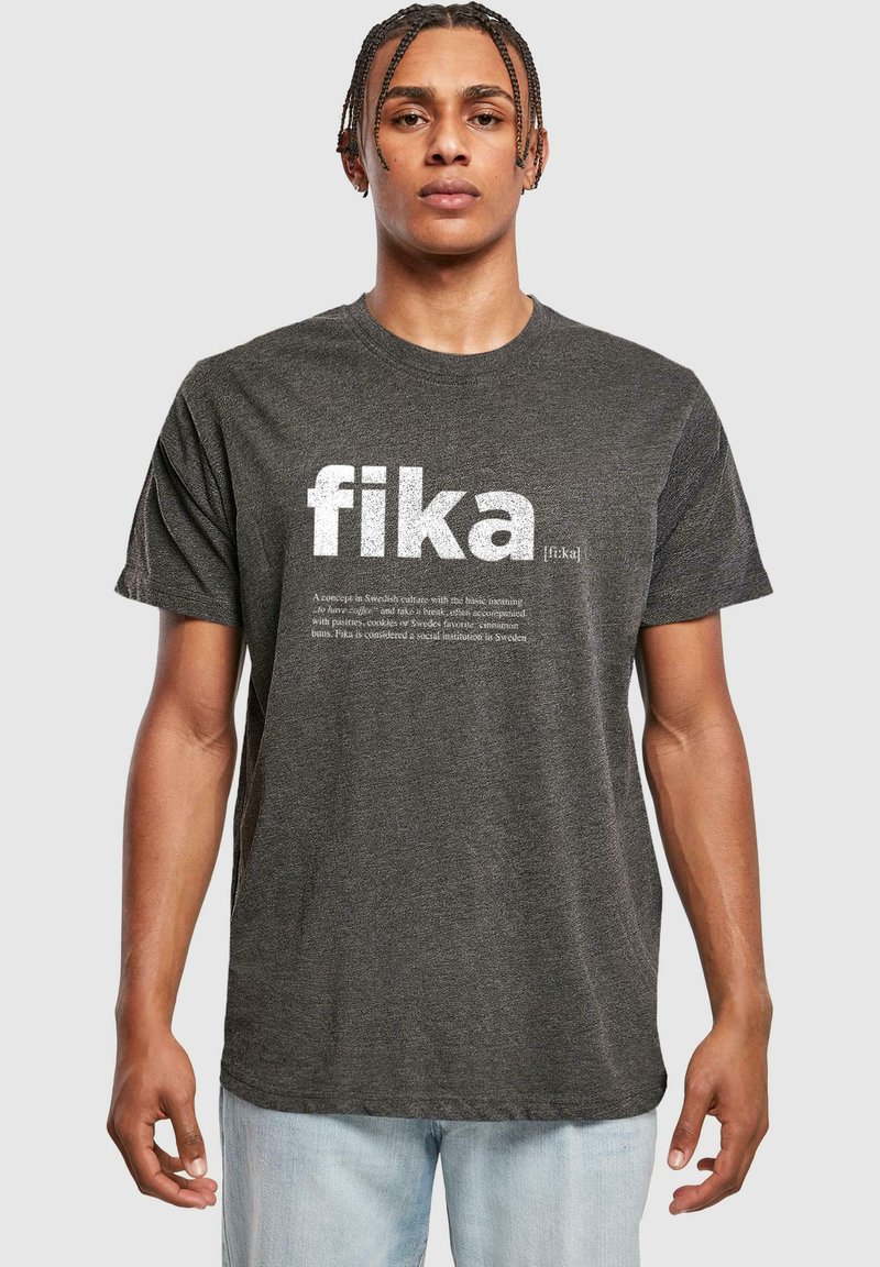 Sötét szürke, rövid ujjú póló, nagy fehér betűkkel „fika” felirattal, alatta kisebb betűmérettel a definícióval. Puha anyag, laza szabás.