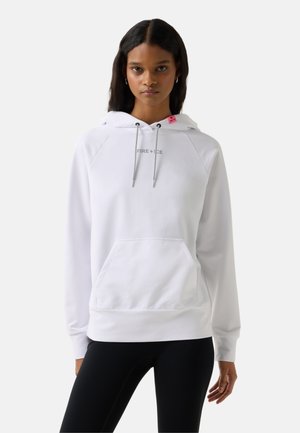 Vrouw draagt een wit hoodie met een voorzak en de tekst "FIRE+ICE", gecombineerd met zwarte leggings, staand tegen een effen achtergrond.
