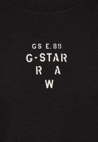 Černé bavlněné tričko s bílým potiskem nápisu "GS E.89 G-STAR R A W" v různých velikostech a zarovnáních, s kulatým výstřihem.