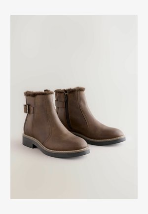 Brune ankelstøvler med kunstpels-for øverst, lynlås i siden og remdetalje. Lavet af glat læder med en lav, kraftig hæl.