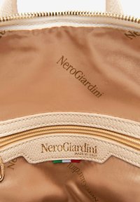 Interno della borsa in nylon beige con una tasca con zip e dettagli in pelle testurizzata. Logo dorato impresso all'interno e accento della bandiera italiana.