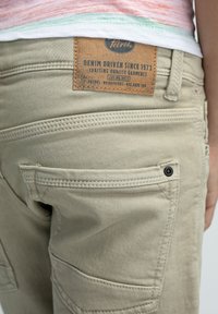 Beige cargobroek met patch pocket details en een leren merklabel. Duurzaam materiaal met ton-sur-ton stiksels en een klassiek pasvorm ontwerp.