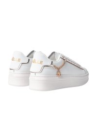 Sneaker bianchi con tomaia in pelle liscia, logo dorato sul tallone e una decorazione a catena sul lato. Suola spessa e bianca.