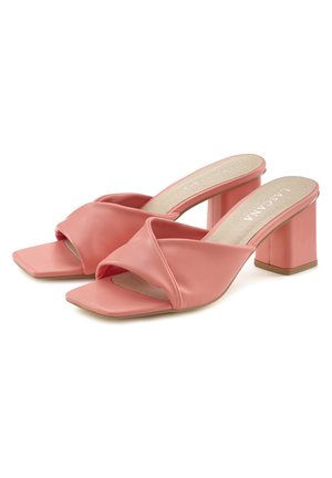 Sandalias de tacón en color coral con punta cuadrada, que presentan una correa frontal retorcida y un tacón ancho. El material parece suave y ligeramente brillante.