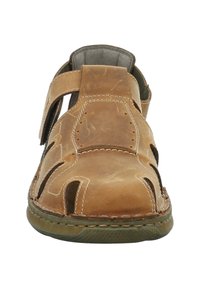 Brown leather sandal with open sides, adjustable strap, stitched detailing, and textured sole. Durable design for breathability and comfort.