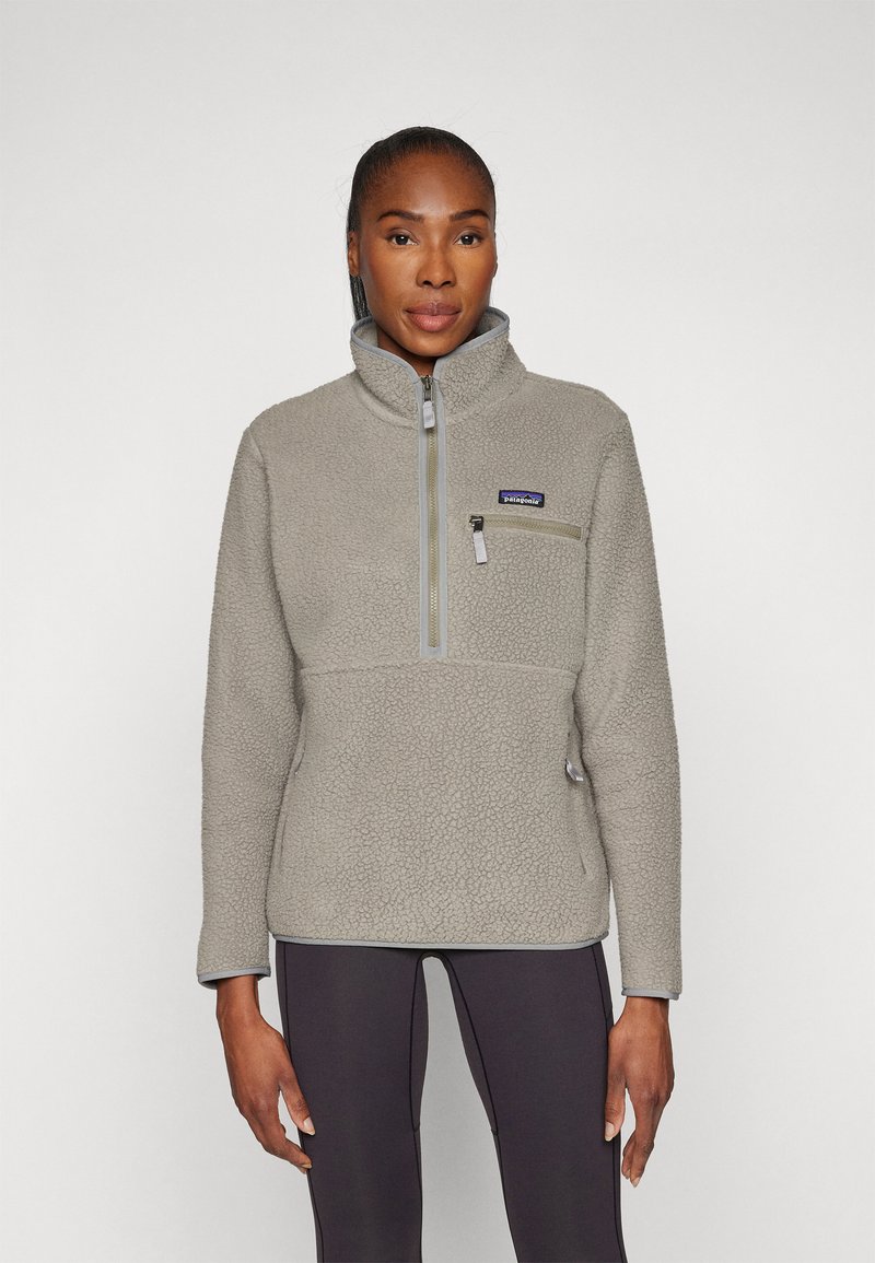 Pullover in pile grigio caratterizzato da una chiusura a mezza zip, colletto alto e tasca sul petto con zip. Superficie texturizzata con dettagli in hardware a contrasto.