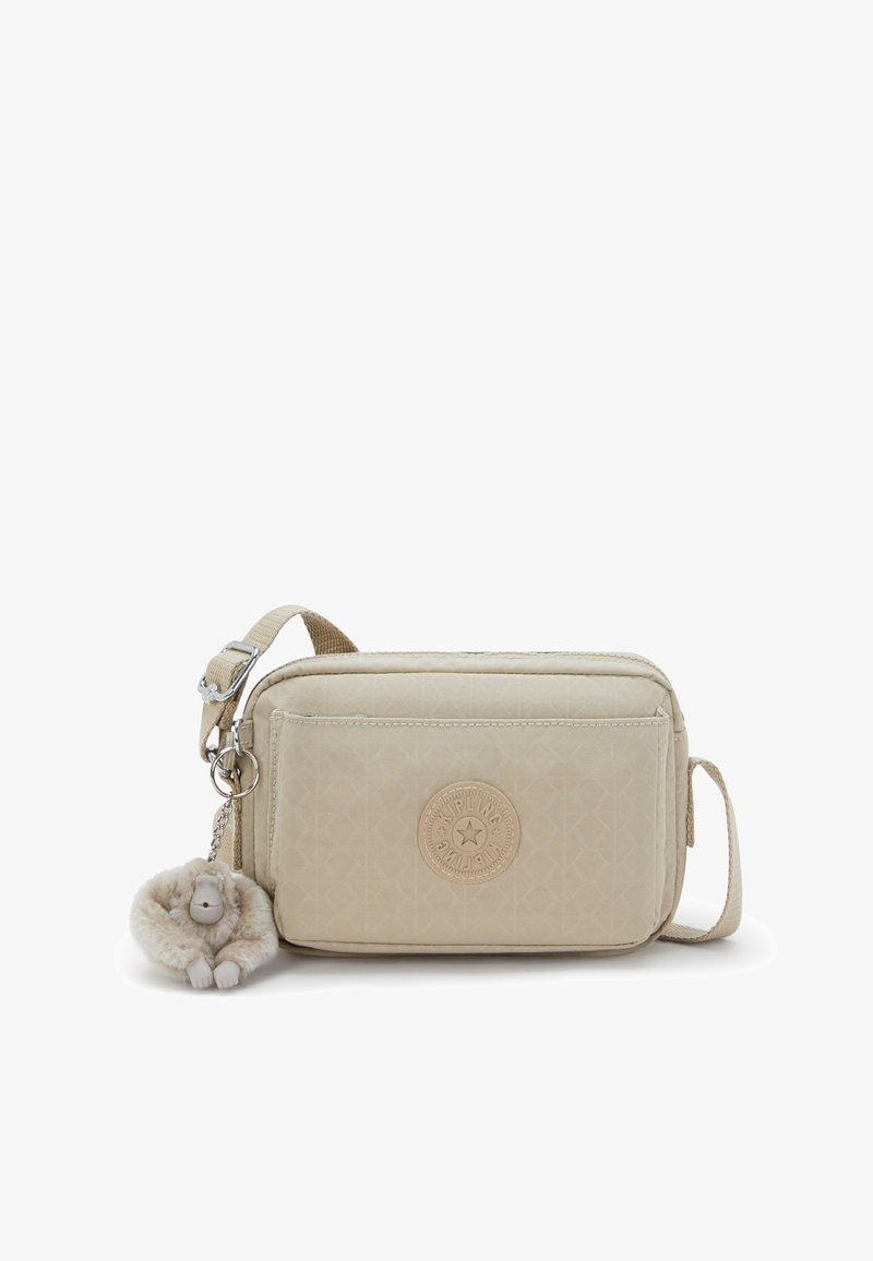 Beige rectangular crossbody bag in textured material, featuring a round logo patch and a plush monkey keychain. Adjustable strap included.