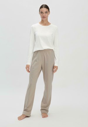 Weißes Langarmoberteil kombiniert mit beigen, elastischen weiten Hosen. Der Stoff wirkt weich, hat eine glatte Textur, ein lässiges Design und eine bequeme Passform.