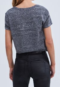 Gray melange T-shirt with short sleeves, featuring printed text "La vie en Rock" on the back. Paired with black denim jeans.