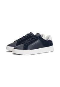 O pereche de adidași navy blue și alb, cu vârf jos și șireți, având logo-ul Tommy Hilfiger pe lateral și pe limbă, expuși pe un fundal alb.