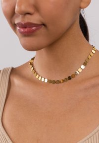 Goldene Choker-Halskette mit runden, flachen Plättchen, die miteinander verbunden sind, mit einer glänzenden Oberfläche. Glatte Textur und minimalistisches Design.