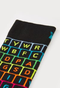 Schwarze Socken mit einem Tastaturdesign, das mehrfarbige Buchstaben in Neon-Gelb, Blau, Grün, Orange und Pink auf dem Stoff zeigt.