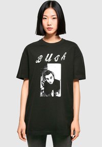 Sort bomulds T-shirt med grafisk print af et sort-hvidt foto med teksten "BUSH" ovenover i en slidt skrifttype. Løs pasform.