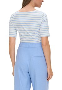 Gestreiftes Kurzarmoberteil in Weiß und Hellblau, kombiniert mit hochtaillierten hellblauen Hosen mit Seitentaschen und glatter Textur.