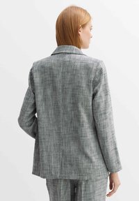 Grijze geblokte blazer met lange mouwen, reverskraag en een relaxte fit. Geweven stof met een subtiele structuur.