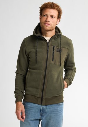 Haut en molleton olive avec fermeture éclair, capuche réglable avec cordon de serrage et détails de poche avant. Tissu texturé et poignets ajustés.