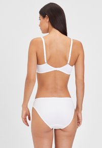 Weißes Dessous-Set bestehend aus einem BH mit verstellbaren Trägern und passendem Slip. Glattes Material, nahtloses Design und zarte Details.