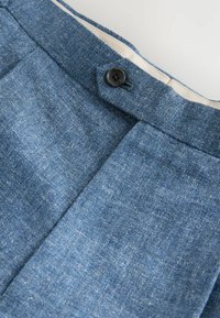 Denimhosen in einem mittleren Blauton mit strukturierter Oberfläche. Verfügt über einen Knopfverschluss und Falten an der Vorderseite. Innen mit cremefarbener Stoff ausgekleidet.