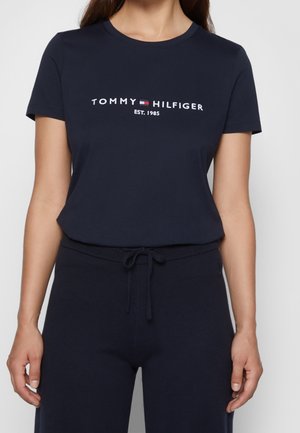 Navy modré bavlněné tričko s krátkým rukávem, zdobené bílou vyšívanou logem "TOMMY HILFIGER EST. 1985" přes hrudník.