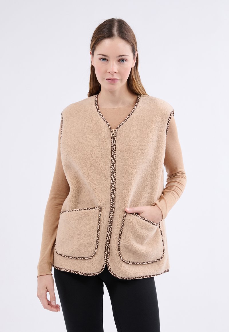 Gilet en polaire beige avec des bordures en imprimé léopard, doté d'une fermeture éclair à l'avant, de deux grandes poches et d'un design à coupe décontractée.