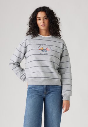 Gray striped sweatshirt with a crew neckline and embroidered design featuring a mountain and sailboat. Paired with blue denim jeans.