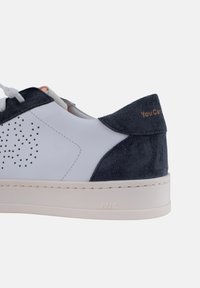 Baskets en cuir blanc avec des accents en daim bleu marine, design perforé, lacets contrastés et détail en texte doré sur le talon. Semelle en caoutchouc.