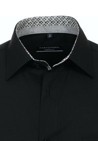 Schwarzes Comfort-Fit-Shirt mit einem gemusterten Kragen in Grau und Weiß, mit einem einzelnen Knopfverschluss und subtiler Textur. Etikett sichtbar im Inneren.