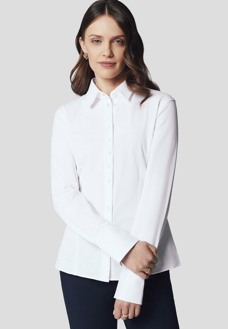 Biała koszula z długim rękawem i kołnierzykiem, charakteryzująca się gładką teksturą i dopasowanym krojem. Guziki ułożone wzdłuż przodu oraz wyprofilowane rękawy.