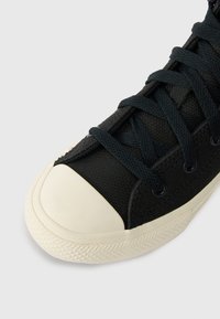 Melnas kanvas kedas ar baltu gumijas purngalu un zoli, ar melnām auklām un teksturētu zoles malu.