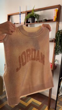 Strikket ærmeløs sweater i lys fersken med ribstrikket tekstur. Har "JORDAN" fremtrædende i mørk ferskenfarvet bogstaver tværs over fronten.