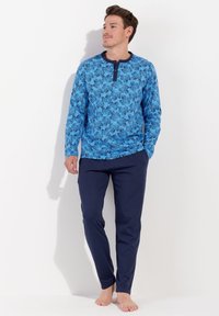 Langärmliges Hemd mit blauem Muster und navyfarbenem Kragen sowie Knopfdetails, kombiniert mit navyfarbigen Hosen, beide aus weichem Material gefertigt.