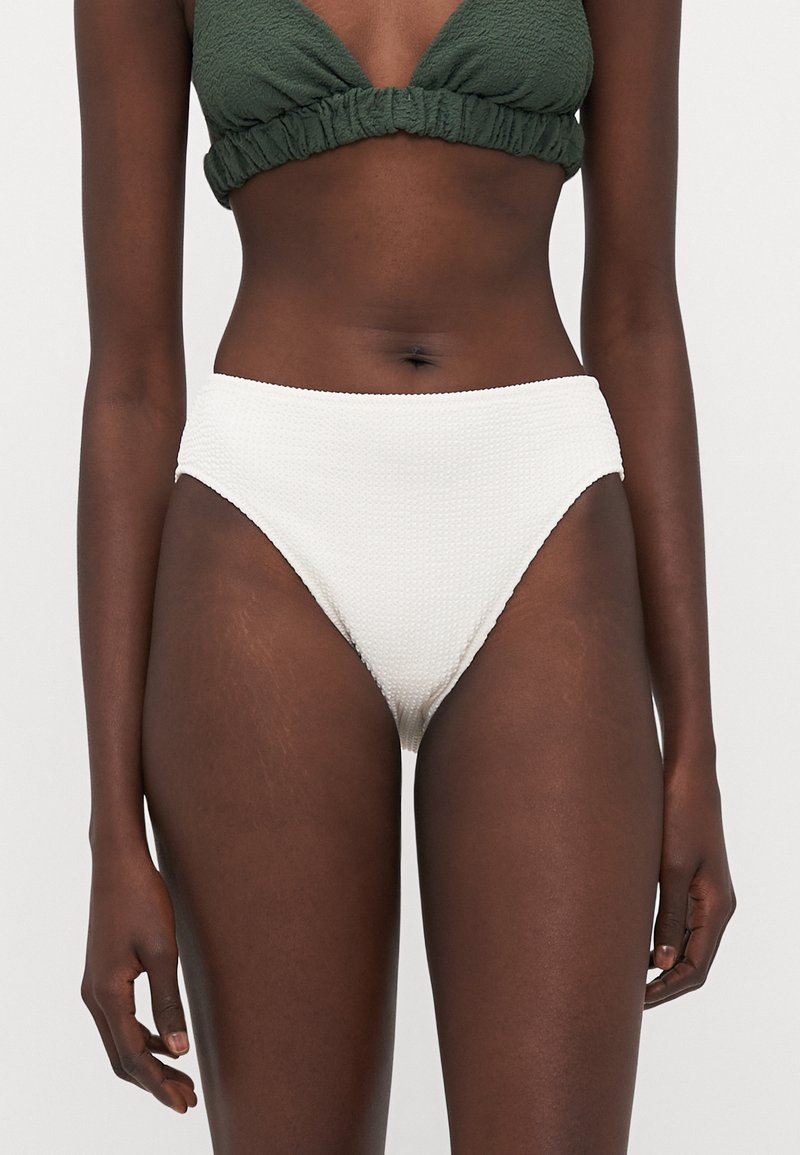 Bikini bottom bianco a vita alta realizzato in materiale testurizzato e rigato. Presenta una cintura liscia e un design con gambe a taglio.