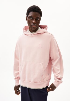 Haut à capuche rose clair avec poche frontale, cordon de serrage et détail de logo brodé. Tissu doux avec poignets et ourlet côtelés.