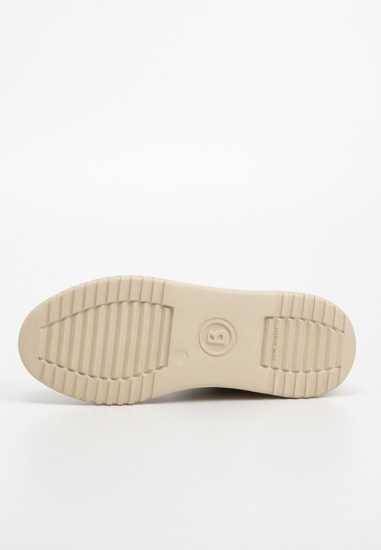Beige Gummisohle mit horizontalen und vertikalen Rillen für mehr Traktion, versehen mit einem runden Logo und einer strukturierten Oberfläche für besseren Grip.