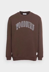 Sudadera marrón con el logo "WOODBIRD" en blanco, cuello redondo, puños y dobladillo acanalados, confeccionada con una suave mezcla de algodón.