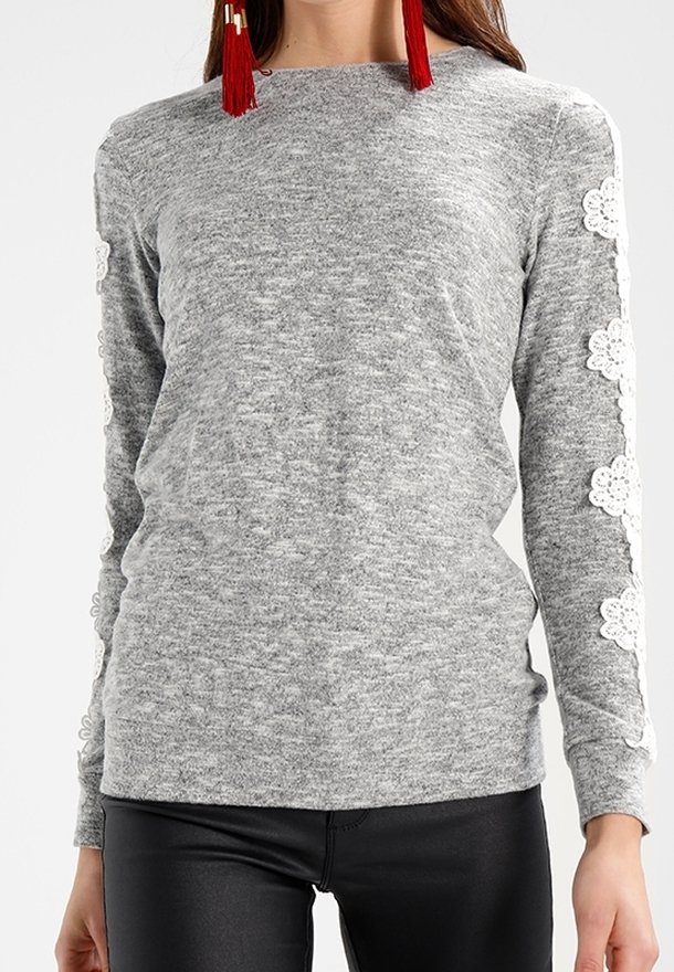 Grå långärmad topp i mjukt tyg med spetstillverkade detaljer längs ärmarna. Rundad halsringning, åtsittande design och slät yta.