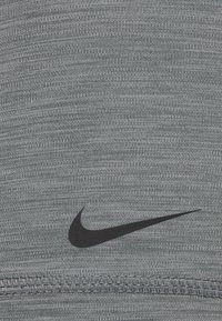 Nike athletic fabric in gray with a textured pattern. Features a black swoosh logo, fine stitching along the hem, and a smooth surface.