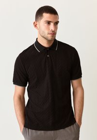 Zwart poloshirt met een gestructureerd diamantenpatroon, korte mouwen en grijze accenten op de kraag en mouwzomen. Twee-knopenbies.