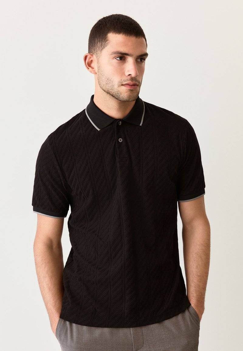 Zwart poloshirt met een gestructureerd diamantenpatroon, korte mouwen en grijze accenten op de kraag en mouwzomen. Twee-knopenbies.