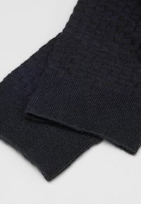 Calcetines de punto en color azul marino oscuro con un patrón texturizado y un cuff acanalado. Fabricados con tela suave y elástica, aptos para uso casual.